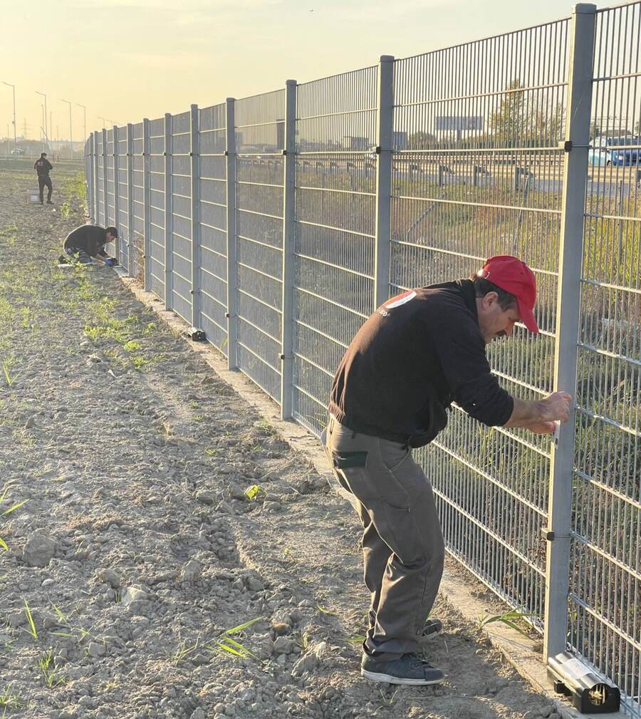 Echipa Compania DDD montează stații pentru rozătoare de-a lungul gardului unui perimetru industrial