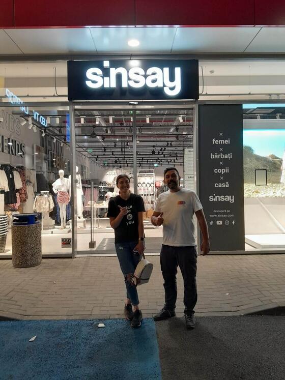 Operatorul Compania DDD alături de o angajată a magazinului, în fața unui Sinsay dintr-un centru comercial